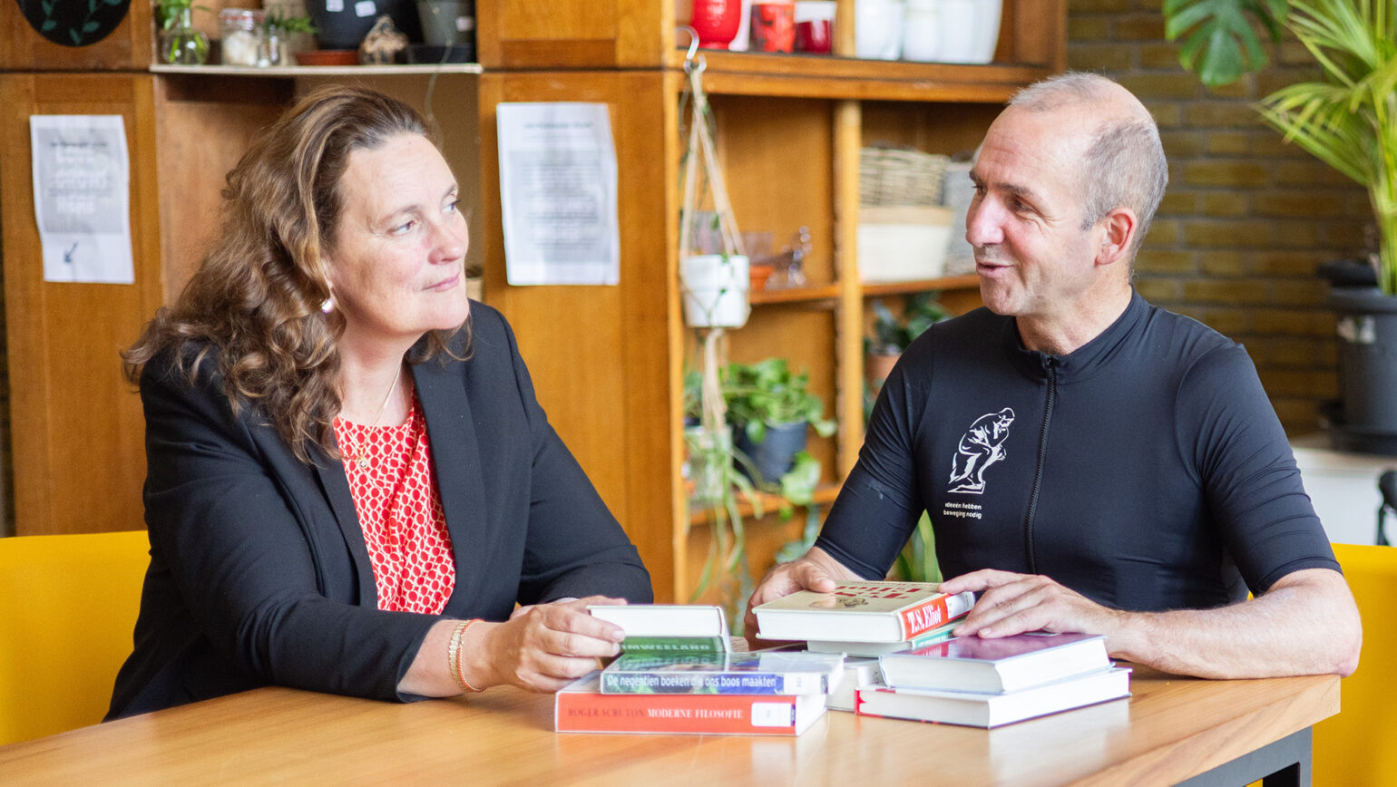 Deirdre Carasso and Menno Hurenkamp talking at a table full of books