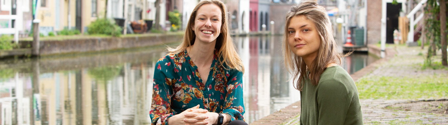 two students sitting by the Oudegracht canal in Utrecht