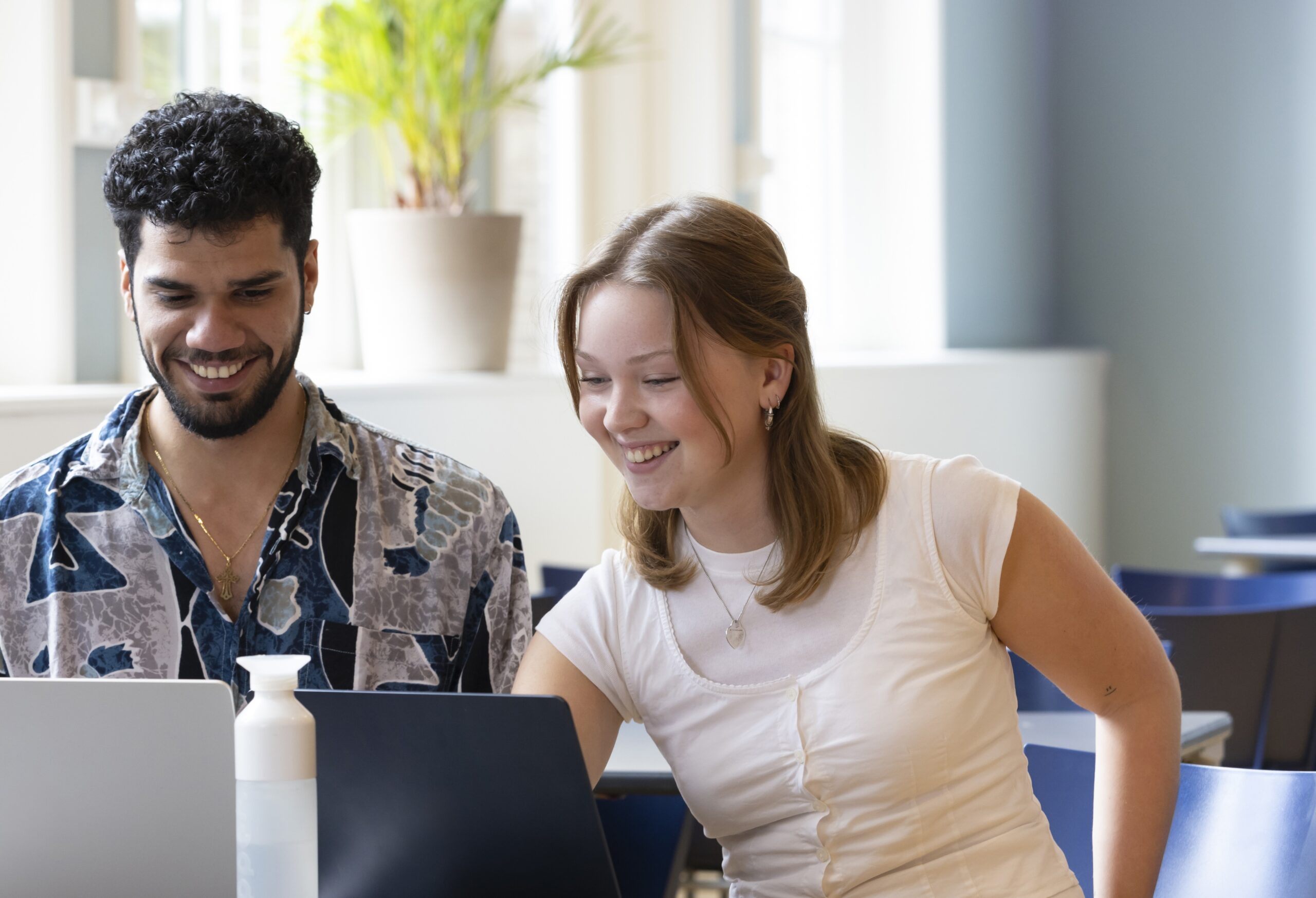 Twee studenten zitten samen achter een computer.