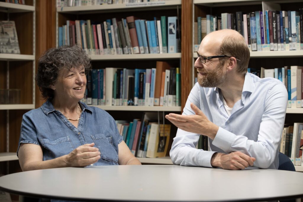 Caroline en Pieter zijn in gesprek met elkaar aan een tafel in de leeszaal