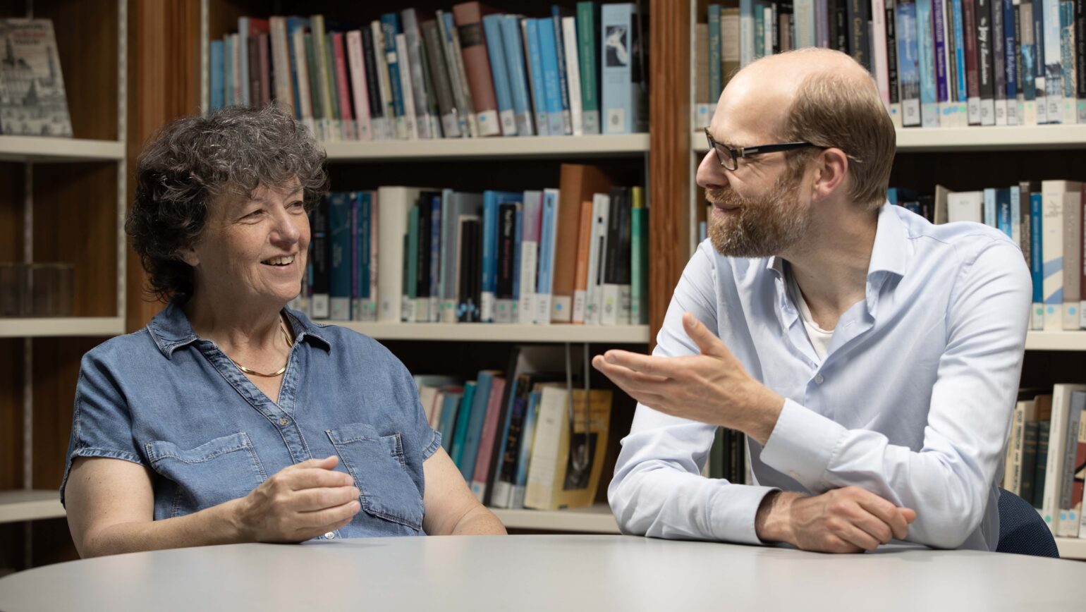 Caroline en Pieter zijn in gesprek met elkaar aan een tafel in de leeszaal