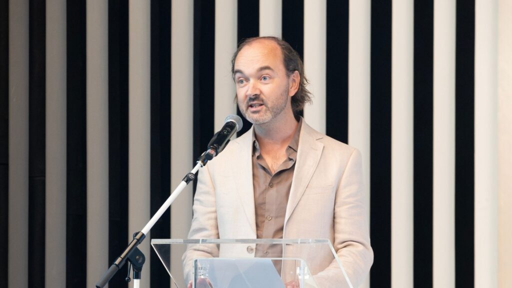 Berend van der Kolk op het podium achter de microfoon